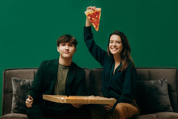 Freunde pinkeln mit Pizza auf dem Sofa Studiofoto auf grünem Hintergrund