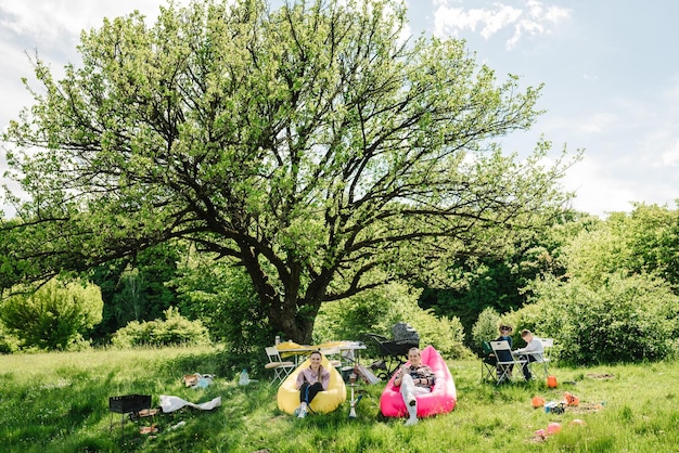 Freunde rauchen Wasserpfeife und entspannen sich in der Natur Eltern mit Kindern bei einem Picknick Freizeiturlaub essen Menschen und Food-Konzept glückliche Freunde bei der Sommergartenparty