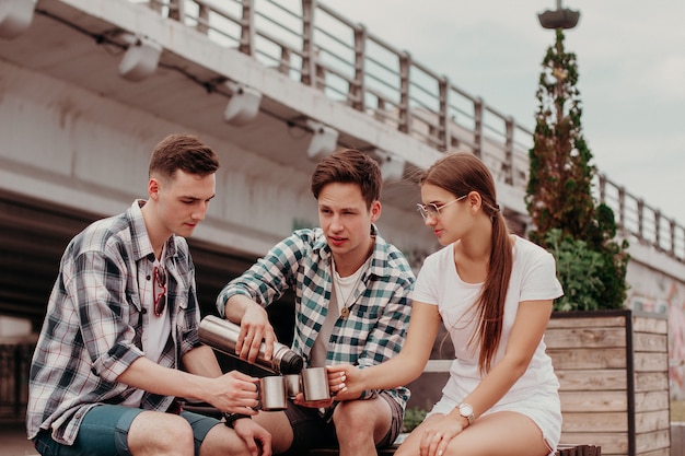 Freunde-Reisende mit Thermoskanne während eines Sommerspaziergangs durch die Stadt