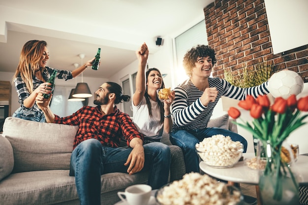 Freunde sind Fans von Sportspielen wie Fußball und verbringen ihre Freizeit gerne gemeinsam zu Hause. Sie schreien und gestikulieren für einen Sieg.