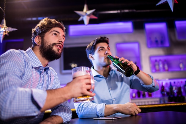 Freunde sitzen an der Theke und trinken Bier