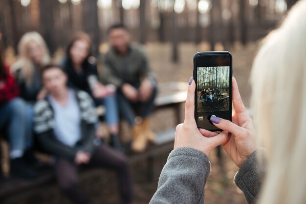 Freunde sitzen draußen im wald. konzentrieren sie sich auf das telefon.