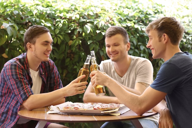 Freunde sitzen im Cafe mit frischem Bier und leckerer Pizza