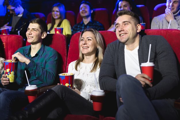 Freunde sitzen und essen Popcorn zusammen, während sie Filme in einem Kino schauen