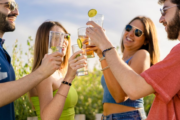 Freunde stoßen auf Party im Freien an. Junge Leute stoßen mit Cocktails im Garten an.