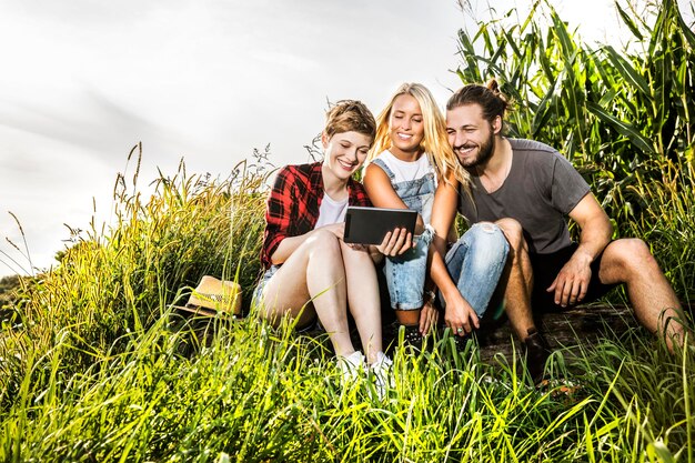 Freunde teilen sich ein Tablet in einem Maisfeld