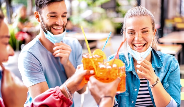 Freunde trinken an der Cocktailbar mit offenen Gesichtsmasken