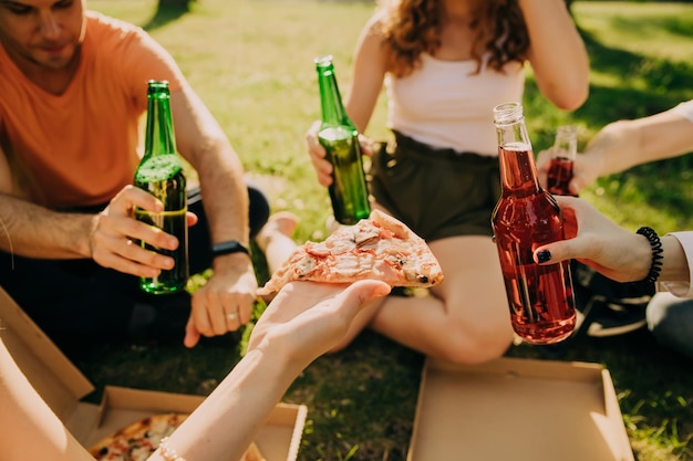 Freunde trinken Bier und Alkohol und essen Pizza im Freien, Hände aus nächster Nähe.