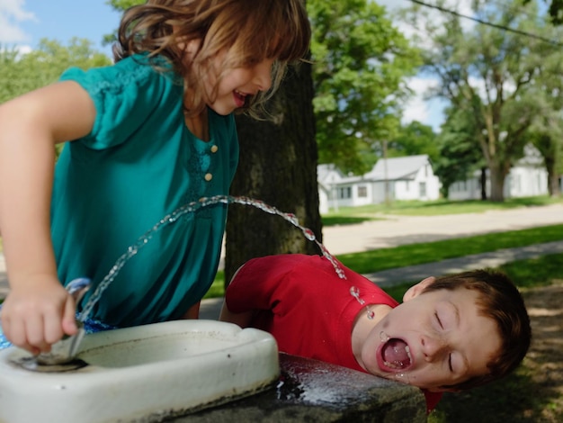 Foto freunde trinken wasser aus dem brunnen