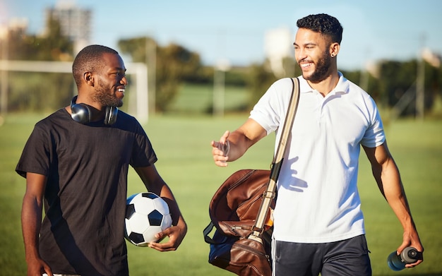 Freunde und Männer von Fußballspielern, die nach dem Training oder Fitnesstraining auf dem Rasenplatz auf dem Fußballplatz spazieren Diversity-Lächeln und Fußballspieler, die nach dem Sporttraining Bindungen oder Diskussionen unterhalten