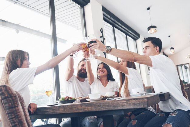 Freunde versammelten sich am Tisch mit leckerem Essen mit Gläsern Rotwein, um einen besonderen Anlass zu feiern