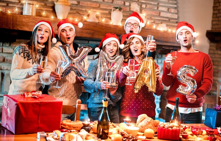 Foto freundesgruppe mit weihnachtsmütze feiert weihnachtszeit mit champagner und süßigkeiten essen bei dinnerparty