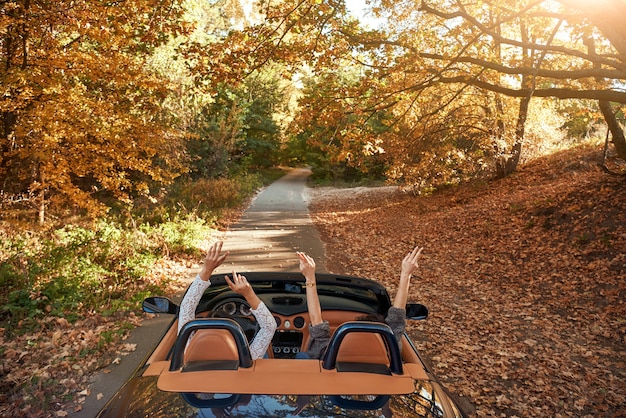 Freundinnen, die Cabriolet mit den Händen nach oben fahren und Spaß haben