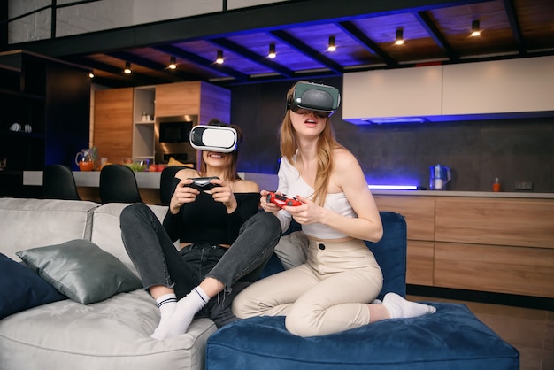 Freundinnen, die zu Hause mit Aufregungsvideospielen spielen, die eine VR-Brille verwenden, um die Urlaubszeit zu genießen