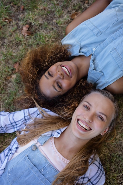 Foto freundinnen, die zusammen auf gras im park liegen