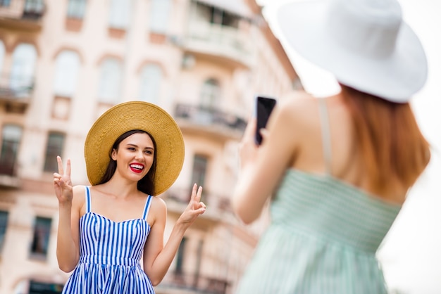 Freundinnen in Sommerkleidern und Strohhüten posieren zusammen