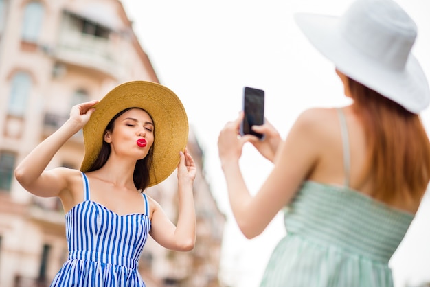 Freundinnen in Sommerkleidern und Strohhüten posieren zusammen