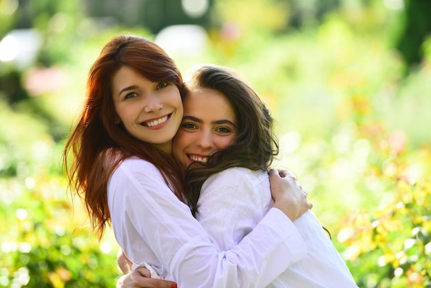 Freundinnen lachen und umarmen sich im Freien Zwei Frauen umarmen sich auf der grünen Wiese