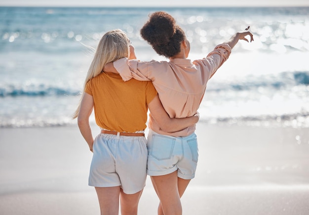 Freundinnen und Umarmungen entspannen sich am Strand für Sommerurlaubsreisen oder gemeinsame Reisen im Freien Interracial Frauen umarmen und genießen Reisereisen oder Abenteuer an der Meeresküste