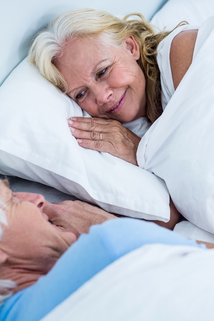 Freundliche ältere Paare, die auf Bett schlafen