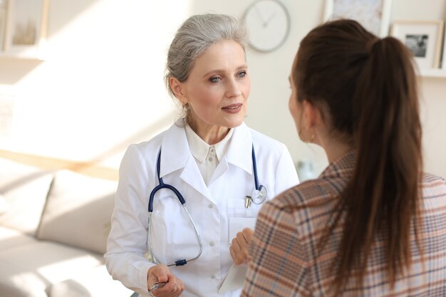 Freundliche Ärztin mittleren Alters, die den Patienten nach der ärztlichen Untersuchung unterstützt.