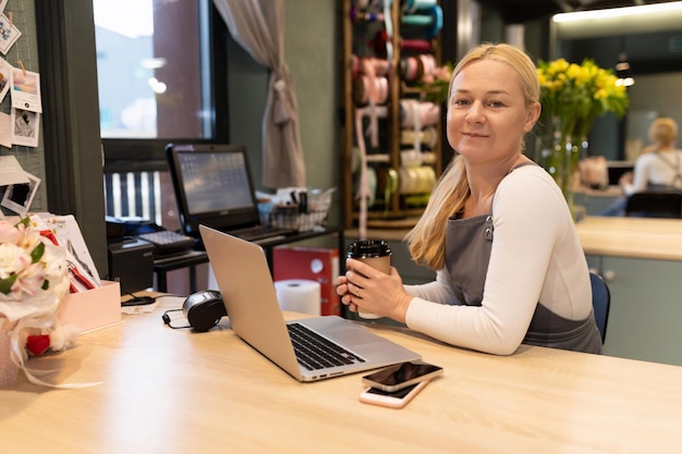 Freundlicher Blumenladenbesitzer, der mit einem Lächeln im Gesicht am Computer arbeitet