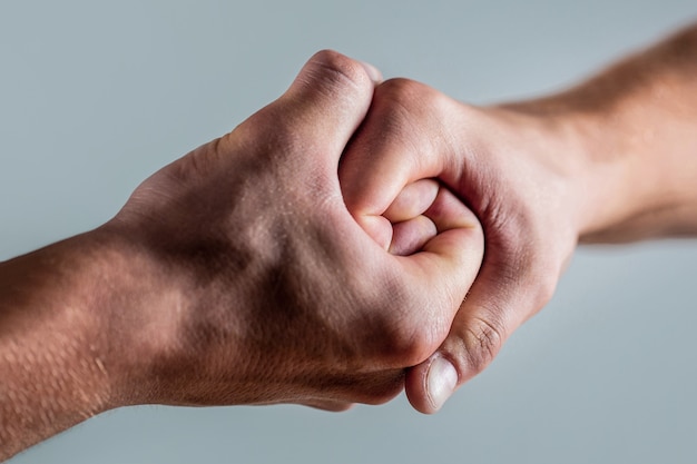 Freundlicher Händedruck, Begrüßung durch Freunde. Rettung, helfende Hand. Männliche Hand im Händedruck vereint.