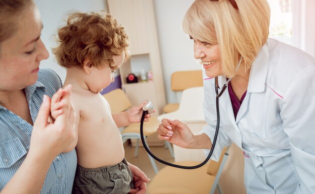 Foto freundlicher kinderarzt mit geduldigem kind in der klinik