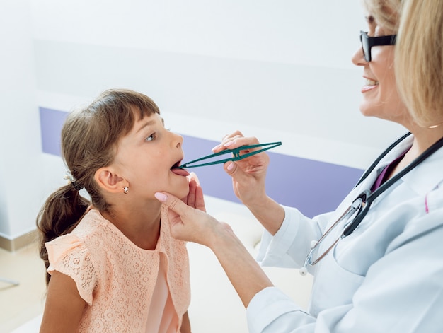 Freundlicher Kinderarzt mit geduldigem Kind in der Klinik