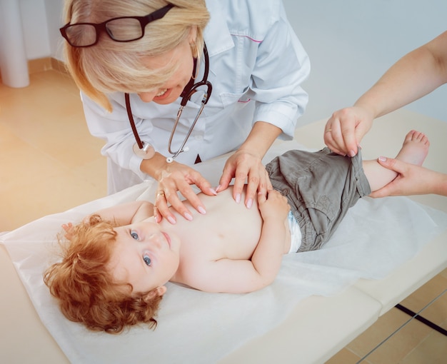 Freundlicher Kinderarzt mit geduldigem Kind in der Klinik