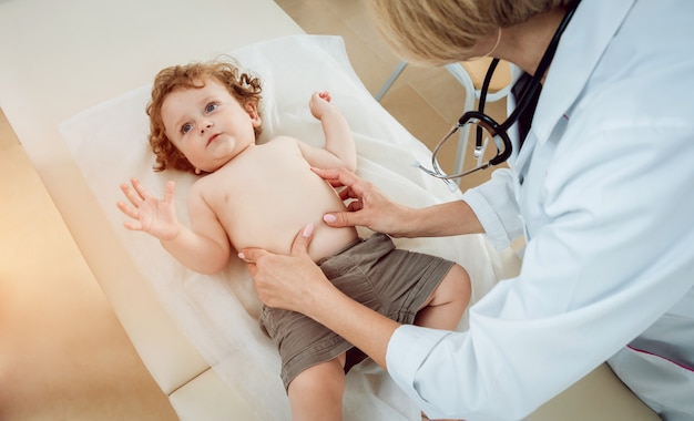 Freundlicher Kinderarzt mit geduldigem Kind in der Klinik