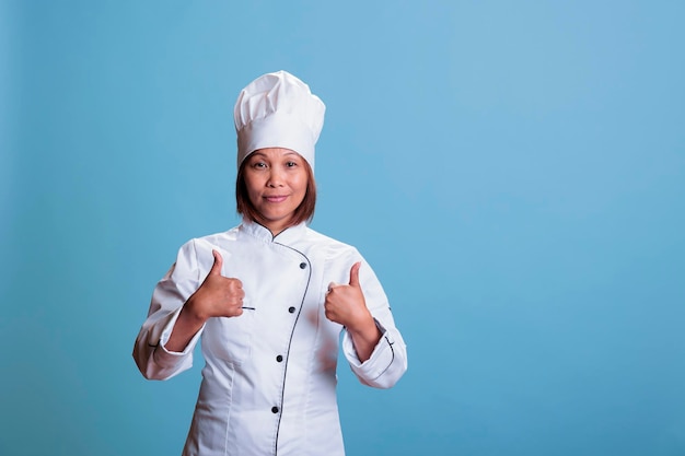 Freundlicher, positiver Koch, der das gastronomische Rezept genehmigt und ein kulinarisches Abendessen mit gesunden Zutaten kocht. erfolgreicher koch, der zulassungszeichen zeigt, speisegericht zubereitet