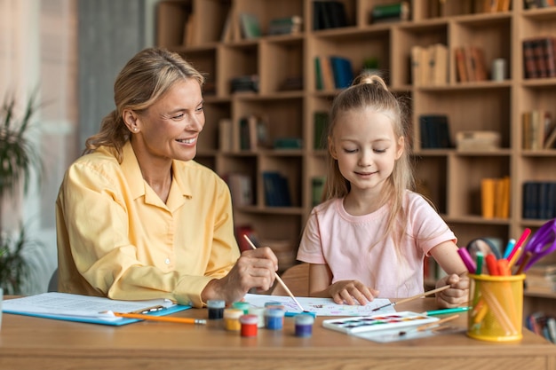 Freundlicher Spezialist für Kinderentwicklung, der mit einer Psychologin für kleine Mädchen zusammenarbeitet, die mit Kindern trainiert