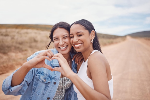 Foto freundschaft herzform und frauen in der natur bei einem urlaubsabenteuer oder wochenendausflug zusammen fröhliches lächeln und beste freundinnen mit liebeshandzeichen oder emoji im urlaub auf dem land