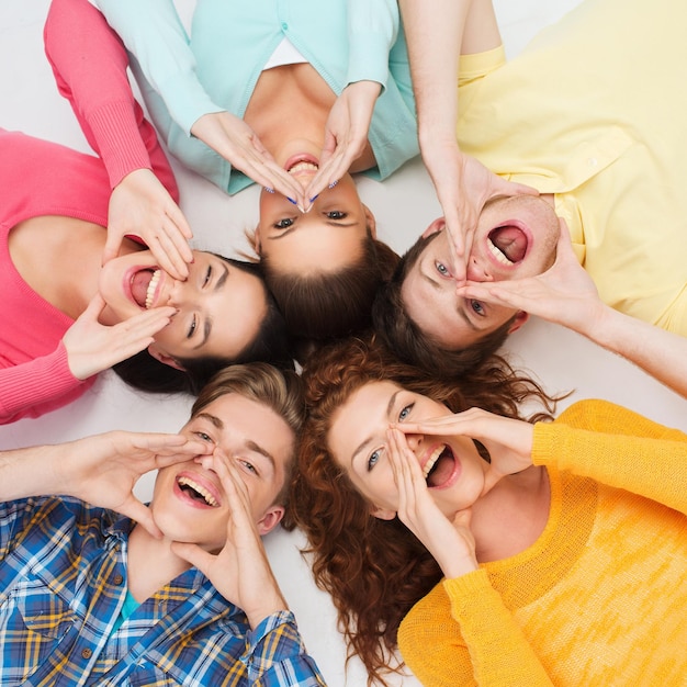 Freundschaft, Jugend, Gesten und Menschen - eine Gruppe lächelnder Teenager, die im Kreis auf dem Boden liegen und schreien