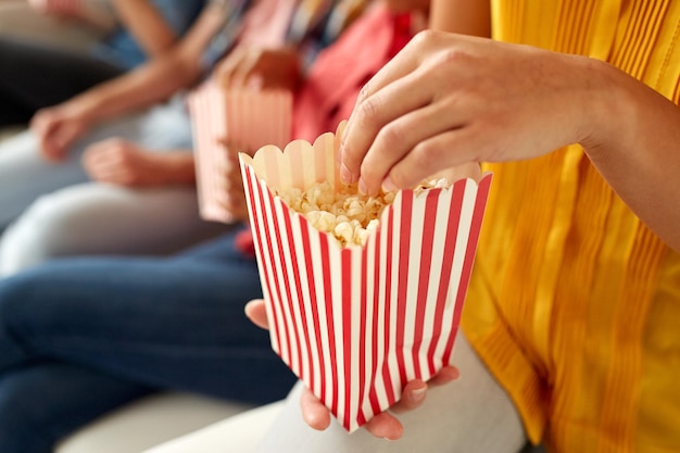 Freundschaft, Junkfood und Menschenkonzept - Nahaufnahme glücklicher lächelnder Freunde, die zu Hause Popcorn essen