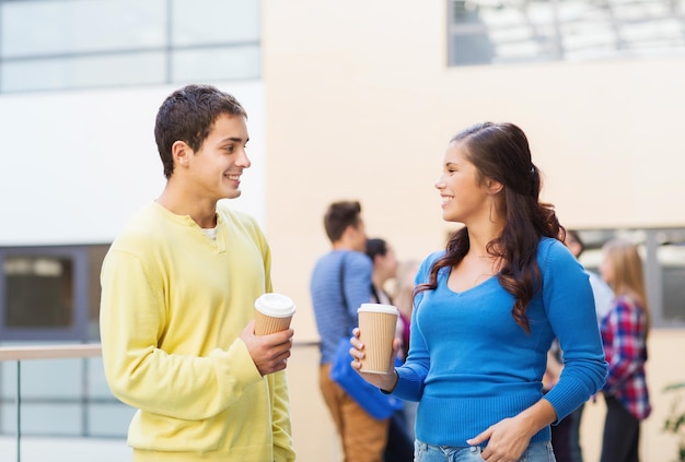 Freundschaft, Menschen, Getränke und Bildungskonzept - Gruppe lächelnder Studenten mit Kaffeetassen aus Papier im Freien