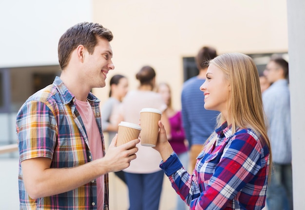 Freundschaft, Menschen, Getränke und Bildungskonzept - Gruppe lächelnder Studenten mit Kaffeetassen aus Papier im Freien