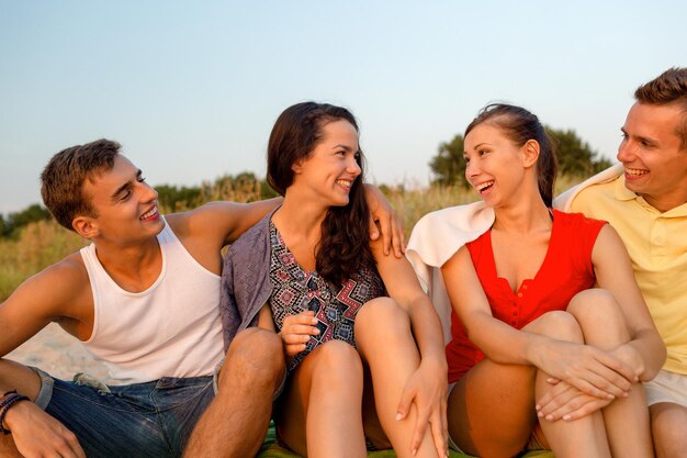 freundschaft, sommerferien, ferien, gesten und personenkonzept - gruppe lächelnder freunde, die am strand sitzen