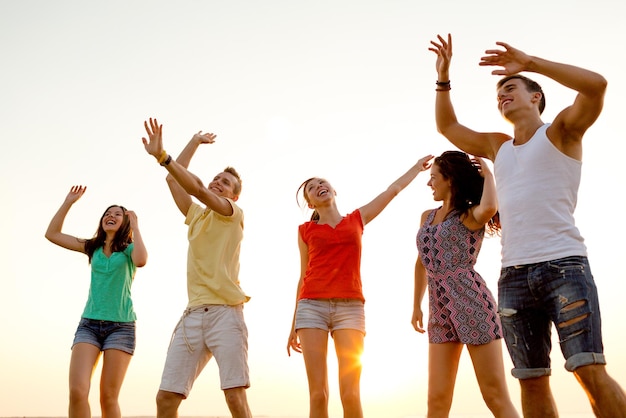 freundschaft, sommerferien, ferien, party und menschenkonzept - gruppe lächelnder freunde, die am strand tanzen