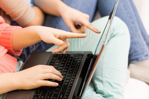 Freundschaft, Technologie, Menschen und Internet-Konzept - Nahaufnahme von jungen Frauen oder Mädchen im Teenageralter mit Laptop-Computer zu Hause