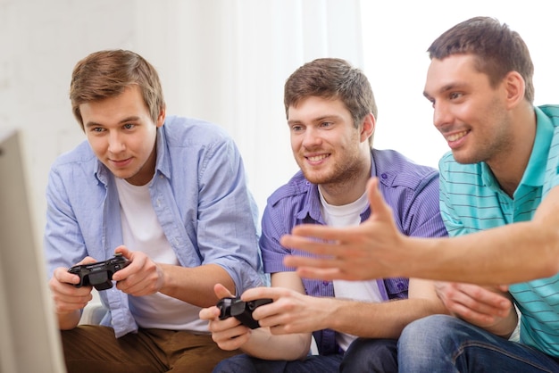 Freundschaft, Technologie, Spiele und Heimkonzept - lächelnde männliche Freunde, die zu Hause Videospiele spielen