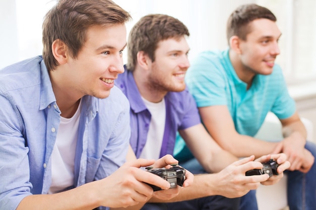 Freundschaft, Technologie, Spiele und Heimkonzept - lächelnde männliche Freunde, die zu Hause Videospiele spielen