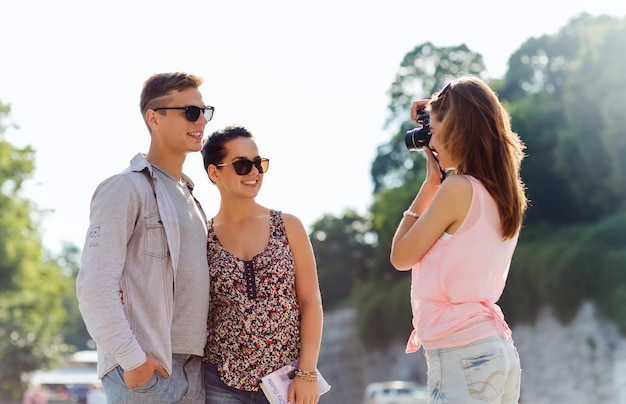 freundschaft, tourismus, sommer, technologie und menschenkonzept - glückliche freunde mit der kamera, die draußen fotografieren