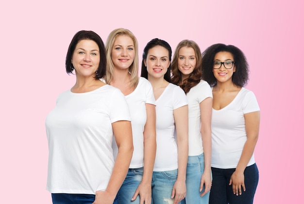 freundschaft, vielfältig, körperpositiv und personenkonzept - gruppe glücklicher frauen unterschiedlicher größe in weißen t-shirts auf rosa hintergrund