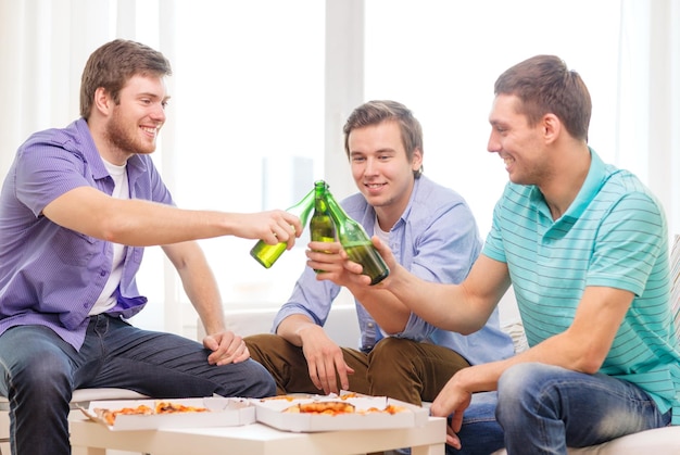 freundschafts-, essens- und freizeitkonzept - lächelnde männliche freunde mit bier und pizza, die zu hause rumhängen