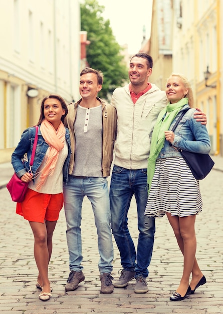 freundschafts-, reise- und urlaubskonzept - gruppe lächelnder freunde, die in der stadt spazieren gehen