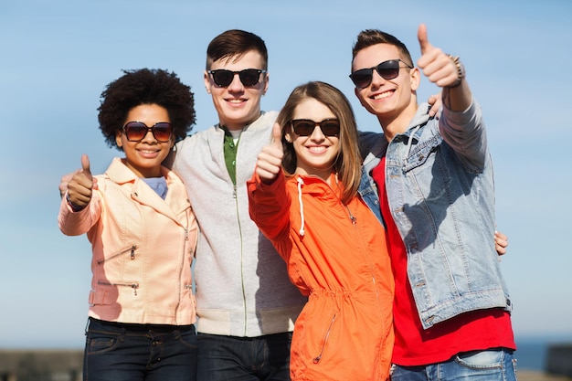 Freundschafts-, Tourismus-, Reise- und Personenkonzept - Gruppe glücklicher Teenager-Freunde mit Sonnenbrille, die sich im Freien umarmen