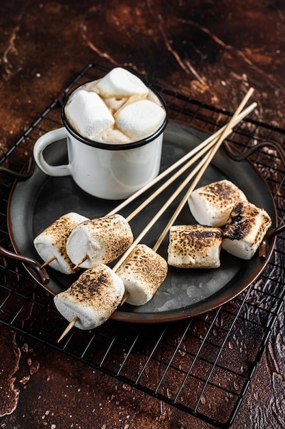 Fried Marshmallow auf den Stöcken mit Tasse Kaffee Dunkler Hintergrund Draufsicht