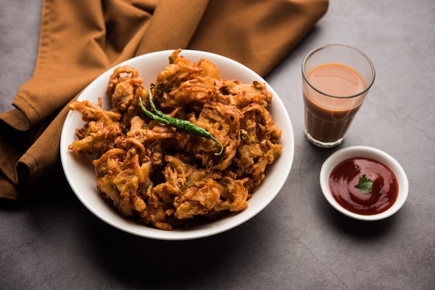 Fried Onion Pakora oder Pyaj Pakoda, auch bekannt als Crispy Kanda Bhaji / Bhajji / Bajji, beliebter indischer Snack zur Teezeit während der Regenzeit. serviert mit Tomatenketchup